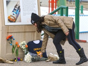 A mourner pays respects at a memorial next to the bobsled and luge track at Canada Olympic Park on Sunday, a day after twins Jordan and Evan Caldwell died when they attempted to slide down the track with six friends early Saturday morning.