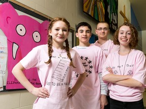 Grade 9 students (L-R) Charlene Harasym, Mateo Rueda, Emily Grant and Kyle van Winkoop pose in pink T-shirts for a photo with a 'Bullying is the elephant in the room' poster at St. Joan of Arc School in Calgary on Tuesday, Feb. 23, 2016.