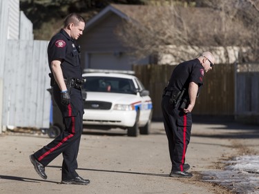Police search the back alley behind a home in the 1800 block of 38 St NE in Calgary, Alta., on Sunday, Feb. 21, 2016. Early reports said shots had been fired into the home, but there was no early confirmation for media. Lyle Aspinall/Postmedia Network