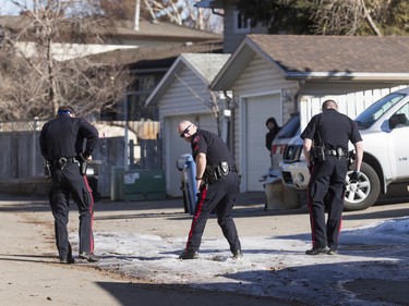 Police search the back alley behind a home in the 1800 block of 38 St NE in Calgary, Alta., on Sunday, Feb. 21, 2016. Early reports said shots had been fired into the home, but there was no early confirmation for media. Lyle Aspinall/Postmedia Network