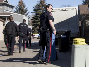 Police search the back alley behind a home in the 1800 block of 38 St NE in Calgary, Alta., on Sunday, Feb. 21, 2016. Early reports said shots had been fired into the home, but there was no early confirmation for media. Lyle Aspinall/Postmedia Network