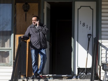 A man talks on his phone outside of a home in the 1800 block of 38 St NE in Calgary, Alta., on Sunday, Feb. 21, 2016. Early reports said shots had been fired into the home, but there was no early confirmation for media. Lyle Aspinall/Postmedia Network