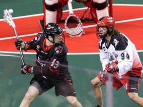 Calgary Roughnecks Tyson Bell moves in a Vancouver Stealth Garrett Billings fires a pass behind his back in NLL action at the Scotiabank Saddledome in Calgary, Alta. on Saturday January 30, 2016. Mike Drew/Postmedia