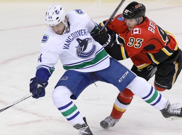 Calgary Flames Sam Bennett hits Vancouver Canucks  Matt Bartkowski in NHL hockey action at the Dome in Calgary, Alta. on Friday February 19, 2016. Mike Drew/Postmedia