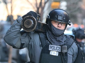A Calgary Police Tactical Unit member carries equipment as cops are involved in an operation in a downtown Calgary apartment building on Thursday, Feb. 25, 2016. Jim Wells/Postmedia