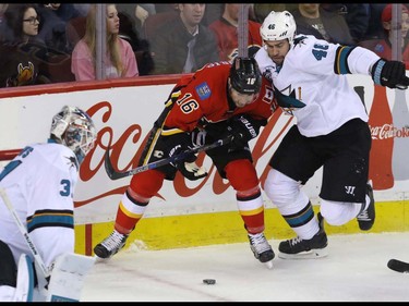 Calgary Flames Josh Jooris is slowed down by San Jose Sharks Roman Polak next to Sharks goalie Martin Jones in NHL hockey action at the Scotiabank Saddledome in Calgary, Alta. on Monday March 7, 2016. Mike Drew/Postmedia