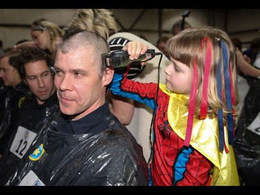 Calgary Firefighter Jim Fisher get his head shaved by Spider-Mable - Mable Tooke - as part of the Calgary Fire Department’s Record-Breaking Head Shave, a fundraising event that is attempting to break the Guinness World Record for most heads shaved simultaneously. The current record sits at 267 people. Over 300 people had their heads shaved in the event, unofficially breaking the record as well as raising over $100,000 for cancer research in Calgary, Ab., on Saturday March 12, 2016. Mike Drew/Postmedia