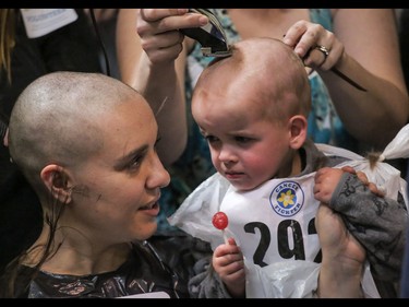 Mom Robin Devine hangs onto son Lucas as they get their heads shaved as part of the Calgary Fire Department’s Record-Breaking Head Shave, a fundraising event that is attempting to break the Guinness World Record for most heads shaved simultaneously. The current record sits at 267 people. Over 300 people had their heads shaved in the event, unofficially breaking the record as well as raising over $100,000 for cancer research in Calgary, Ab., on Saturday March 12, 2016. Mike Drew/Postmedia