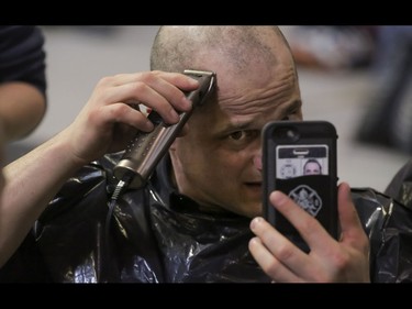 Firefighter Brad Olsen makes sure there are no stray hairs left standing as he and others get their heads shaved as part of the Calgary Fire Department’s Record-Breaking Head Shave, a fundraising event that is attempting to break the Guinness World Record for most heads shaved simultaneously. The current record sits at 267 people. Over 300 people had their heads shaved in the event, unofficially breaking the record as well as raising over $100,000 for cancer research in Calgary, Ab., on Saturday March 12, 2016. Mike Drew/Postmedia