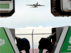 A jet takes off from Calgary International Airport framed between two gas pumps at a station on the south end of the airport, near the Esso aviation facility