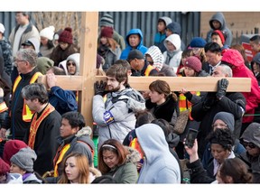 Majid Shammas, centre, helps his family carry a large wooden cross through Calgary on Friday, March 25, 2016. Carrying the cross is significant to many, so people alternate carrying it for a short distance during the two-hour event.