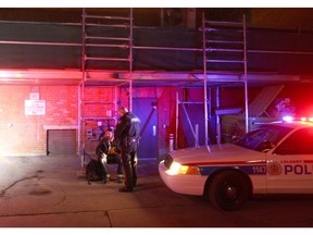 Calgary Police question a man at the scene of a death in the alley between 9 Ave and 8 Ave, just west of 1 St SW in downtown Calgary on Tuesday, March 1, 2016. The death was later deemed non-suspicious.