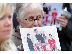 Shelley Barnard, a family friend of Alison Azer , hold s family photo of Alison and her children at a protest Monday urging the government to do more to return the children to Canada.