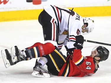 Garnet Hathaway of the Calgary Flames gets tangled up with Trevor van Riemsdyk of the Chicago Black Hawks during the first period at the Saddledome Saturday March 26, 2016.