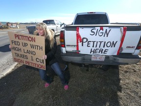 Laurie Kruse Bold holds a sign on Rainbow Road in Chestermere, urging residents to sign a petition. Some residents are protesting the recent utilities increase, high taxes and what the group calls "the lack of transparency & accountability of Tax Payers dollars."