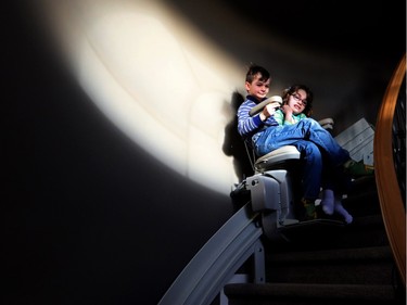 Noah Francis, 8, rides the stair lift with his sister Emma, 12. Emma loves spending time with her brother.