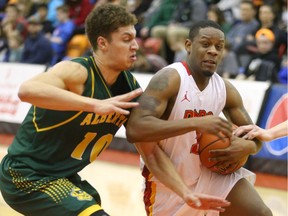 Dinos' Thomas Cooper goes to the hoop past Golden Bears' Brody Clarke, left, during Game 1 of the Canada West men's basketball playoff series between the University of Calgary Dinos and the University of Alberta Golden Bears in Calgary on Friday.