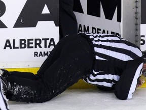 JANUARY 27, 2016 - A linesman goes down after colliding with the Calgary Flames' Dennis Wideman in the second period of NHL action against the Nashville Predators at the Scotiabank Saddledome.