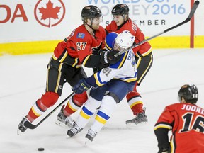 Dougie Hamilton and Jyrki Jokipakka of the Calgary Flames collide with Vladimir Tarasenko of the  St. Louis Blues during the Flames' 7-4 win on Monday.