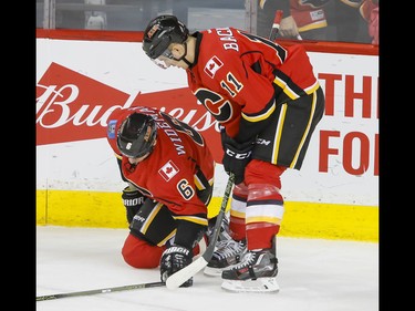 A hurt Dennis Wideman of the Calgary Flames is watched by teammate Mikael Backlund after a Michael Frolik goal against the Winnipeg Jets in Calgary, Alta., on Wednesday, March 16, 2016. The Flames won 4-1. Lyle Aspinall/Postmedia Network