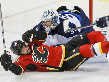 Brandon Bollig of the Calgary Flames falls in front of Winnipeg Jets goalie Ondrej Pavelec in Calgary, Alta., on Wednesday, March 16, 2016. The Flames won 4-1.