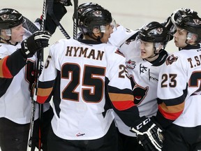 Dawson Martin, centre, celebrates the Calgary Hitmen's third goal of the game against the Saskatoon Blades with teammates, from left, Micheal Zipp, Aaron Hyman and Taylor Sanheim in the third period at the Saddledome on Tuesday night.