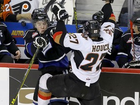 Calgary Hitmen Jackson Houck collides with Victoria Royals Marsel Ibragimov in front of the Royals bench in WHL action at the Scotiabank Saddledome in Calgary, Alberta, on Friday, February 26, 2016. (Mike Drew/Postmedia)