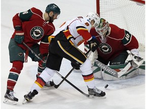 Calgary Flames' Joe Colborne, center, tries to work a rebound as Minnesota Wild goalie Devan Dubnyk and Marco Scandella, left, defend in the first period of an NHL hockey game, Thursday, March 24, 2016, in St. Paul, Minn.