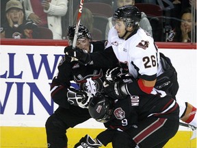 Joel Broda, right, and the Calgary Hitmen hope to squeeze by Ryan Nugent-Hopkins, bottom, and the Red Deer Rebels three times in the club's final 10 tilts.