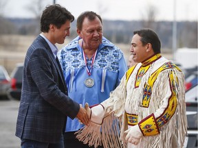 Prime Minister Justin Trudeau, left, is greeted by Tsuu T'ina Chief Roy Whitney, centre, and National Chief Perry Bellegarde as he arrives on the Tsuut'ina First Nation near Calgary on Friday.