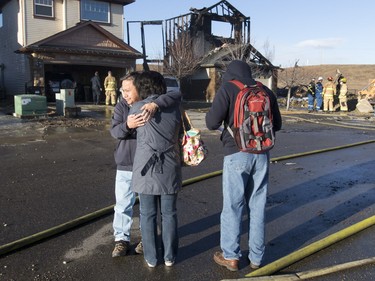Family members embrace outside a row of burned-up homes on Kincora Dr NW in Calgary, Alta., on Tuesday, March 8, 2016. Four homes went up in flames overnight, but no one was injured.