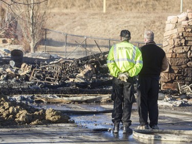 A homeowner stands looking at the remains of his house on Kincora Drive N.W. on Tuesday morning after a major fire.