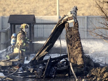 A firefighter sprays water as crews worked to ensure hotspots were extinguished at the scene of an overnight fire in Kincora.