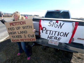 Laurie Kruse Bold holds a sign on Rainbow Rd in Chestermere, Alta, east of Calgary, Alta urging residents to sign a petition on Sunday March 13, 2016. Some members in the town are protesting the recent utililities increase high taxes and what the group calls "the lack of transparency & accountability of Tax Payers dollars." Jim Wells//Postmedia