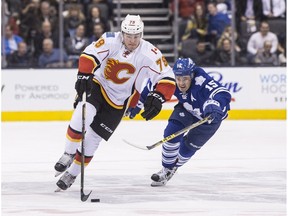 Calgary Flames' Michael Ferland, left, skates the puck away from Toronto Maple Leafs' Pierre-Alexandre Parenteau during first period NHL hockey action in Toronto on Monday, March 21, 2016.