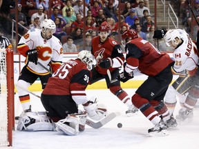 Arizona Coyotes' Louis Domingue (35) makes a save as Calgary Flames' Mikael Backlund (11), of Sweden, battles with Coyotes' Zbynek Michalek (4), of the Czech Republic, for the puck while Flames' Emile Poirier (28) and Coyotes' Kevin Connauton (44) watch during the first period of an NHL hockey game Monday, March 28, 2016, in Glendale, Ariz.