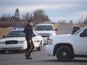 An RCMP officer walks past police vehicles blocking the road towards the Muslim Cemetery outside of Cochrane on Friday, March 11, 2016.