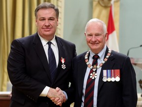 Murray Edwards, left, made a member of the Order of Canada by Gov. Gen. David Johnston in 2014, is a resident of London, U.K., according to a new regulatory filing by Canadian Natural Resources.