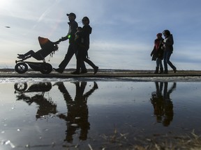 People walk past a puddle in North Glenmore Park in Calgary, Alta., on a warm Monday, Feb. 8, 2016.