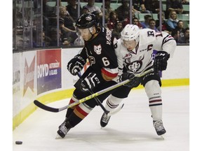 Colby Harmsworth of the Calgary Hitmen and Luke Philp of the Red Deer Rebels battle for the puck behind the net during WHL playoff action at the Enmax Centrium in Red Deer, Alta. Saturday, March 26.