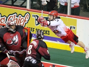 The Calgary Roughnecks' Curtis Dickson goes airborne to try and score on Colorado Mammoth goalie Alex Buque during National Lacrosse League action at the Scotiabank Saddledome on Saturday March 19, 2016.