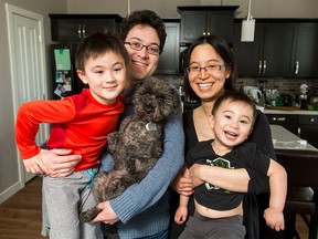 Geoff and Evelyn Tanaka smile with their sons Alex (L), 6, and Sam, 3, and dog Molly inside their home in Calgary on Tuesday, March 15, 2016. The Tanaka family is forgiving robbers who left their new home mostly bare recently, and generosity from community and family is giving them back some of the things they lost. (Lyle Aspinall/Postmedia Network)