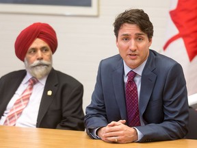 Prime Minister Justin Trudeau sits next to MP Darshan Kang at the Kerby Centre in downtown Calgary, Alta., on Tuesday, March 29, 2016. Trudeau was part of a roundtable discussion on employment insurance at the Kerby Centre before touring a carpentry lab at SAIT Polytechnic.