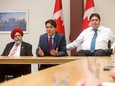 Prime Minister Justin Trudeau sits next to MP Darshan Kang and MP Kent Hehr at the Kerby Centre in downtown Calgary, Alta., on Tuesday, March 29, 2016