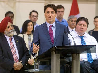 Prime Minister Justin Trudeau is flanked by MPs Darshan Kang and Kent Hehr, and a bevy of roundtable participants, after a roundtable discussion at the Kerby Centre in Calgary, Alta., on Tuesday, March 29, 2016. Trudeau was part of a roundtable discussion on employment insurance at the Kerby Centre before touring a carpentry lab at SAIT Polytechnic.