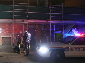 Calgary police question a man at the scene of a death in the alley between 9 Ave and 8 Ave, just west of 1 St SW in downtown Calgary on Tuesday, March 1, 2016. Emergency crews were called to the scene about 8:15 pm and police continue to investigate.