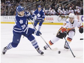 Toronto Maple Leafs' William Nylander, left, shoots on Calgary Flames goaltender Jonas Hiller as Flames' Mikael Backlund, right, defends during second period NHL hockey action in Toronto on Monday, March 21, 2016.