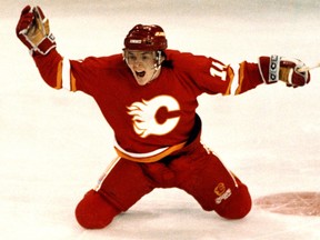 Calgary Flames winger Theoren Fleury celebrates as he slides across the ice after scoring against Edmonton Oilers goalie #31 Grant Fuhr in overtime during game 6 on April, 14, 1991, at Northlands Coliseum in Edmonton.