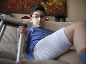 FILE PHOTO: Ali Hassan, 12, sits in his home with his bandage wrapped leg in Calgary, on April 1, 2016. Hassan was badly bitten by a police dog in his home on March 30.