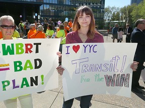 Two supporters, on opposite sides of the issue, hold their signs at a rally at City Hall Wednesday.